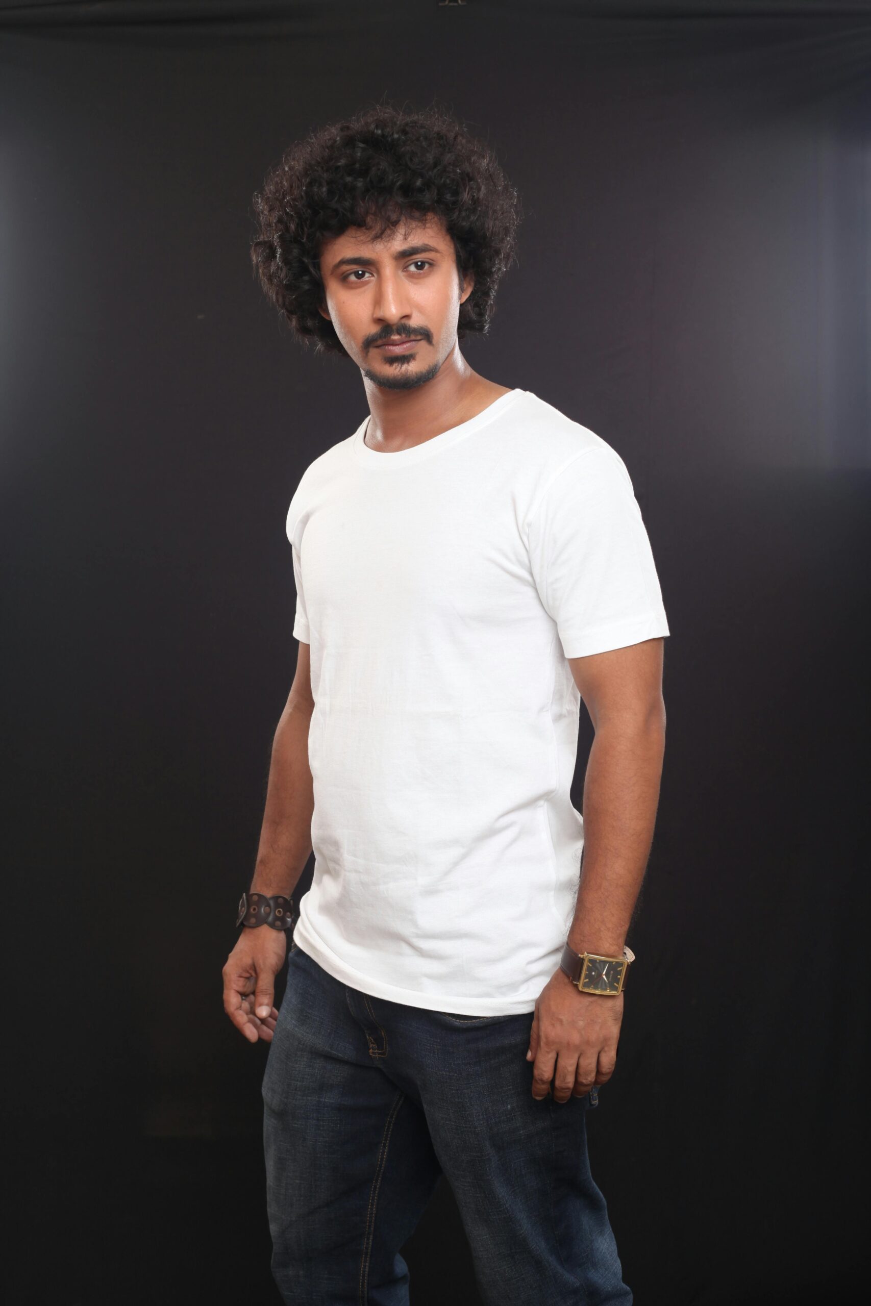 Portrait of a fashionable man in casual attire against a dark background, showcasing modern style.